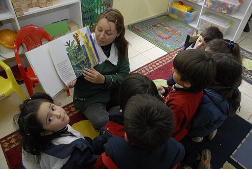 Maestra explicando y leyendo un libro a sus alumnos.